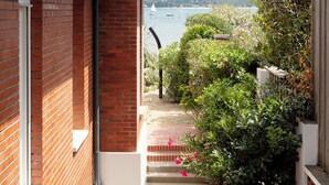 A brick building with a view of the sea, steps leading to a garden with shrubs and flowers. - Villa Les Mouettes, Cap Ferret (Lège-Cap-Ferret)