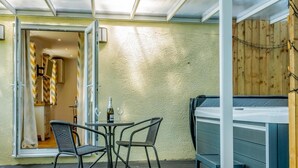 Eine Terrasse mit Whirlpool, zwei Stühlen, einem Tisch und einem Holzzaun.