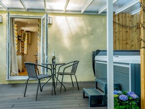 Eine Terrasse mit Whirlpool, zwei Stühlen, einem Tisch und einem Holzzaun.