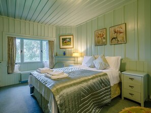 A bedroom with a bed, bedside tables, a chair, a window with curtains, and wall art. - 5 Bed in Inverness (oc-78538) (Drumnadrochit)