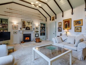 A cozy living room with a fireplace, a television, a white sofa, and a glass coffee table. - 5 Bed in Inverness (oc-78538) (Drumnadrochit)