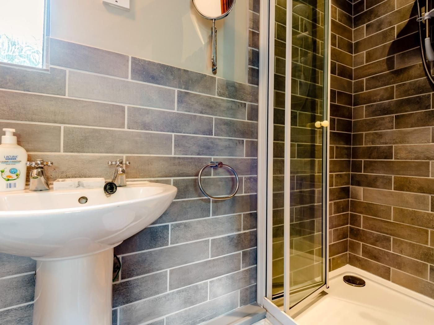 A bathroom with a white sink, a mirror, and a shower with a glass door.