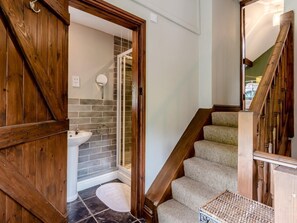 Un escalier en bois mène à une salle de bain équipée d’un lavabo et d’un miroir.