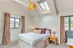 Een slaapkamer met dakraam, een bed, nachtkastjes en gordijnen.