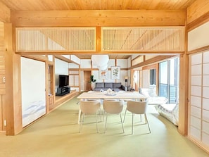 A spacious living area with a central island, a television, and a sofa. - Spacious Traditional Japanese House By Restavio (Ozu)
