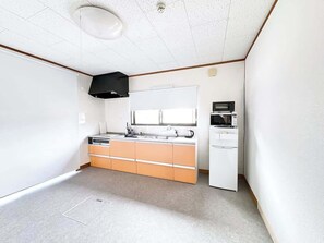 A compact kitchen with a white refrigerator, a microwave, and a sink. - Spacious Traditional Japanese House By Restavio (Ozu)