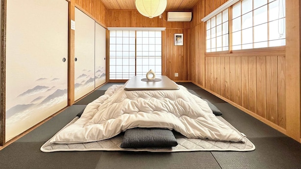 Ett traditionellt japanskt rum med tatamimattor på golvet, en futonmadrass, skjutdörrar och en shojiskärm.