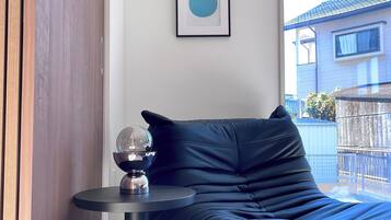 A modern room with a black leather sofa, a small round table with a decorative object, and a framed picture on the wall.
