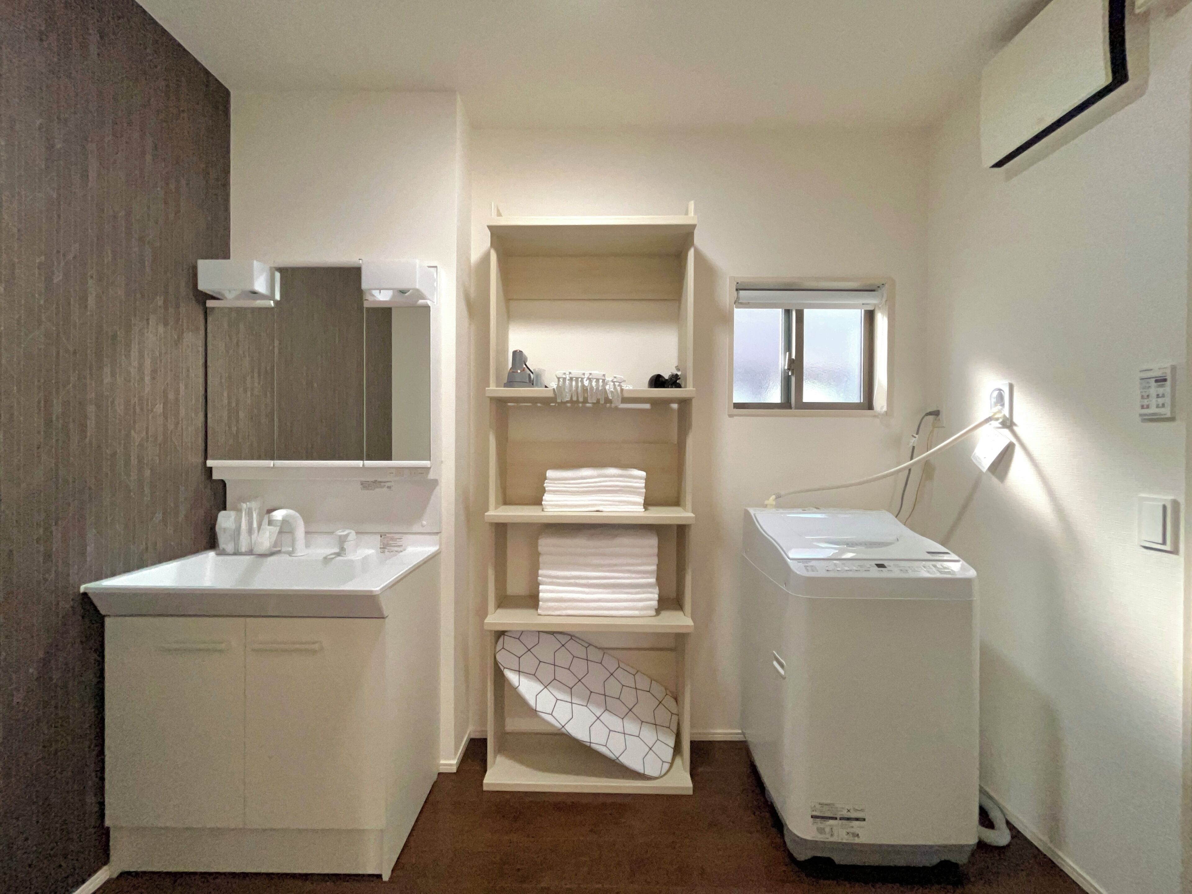 A modern bathroom with a white sink, mirror, and built-in laundry machine.