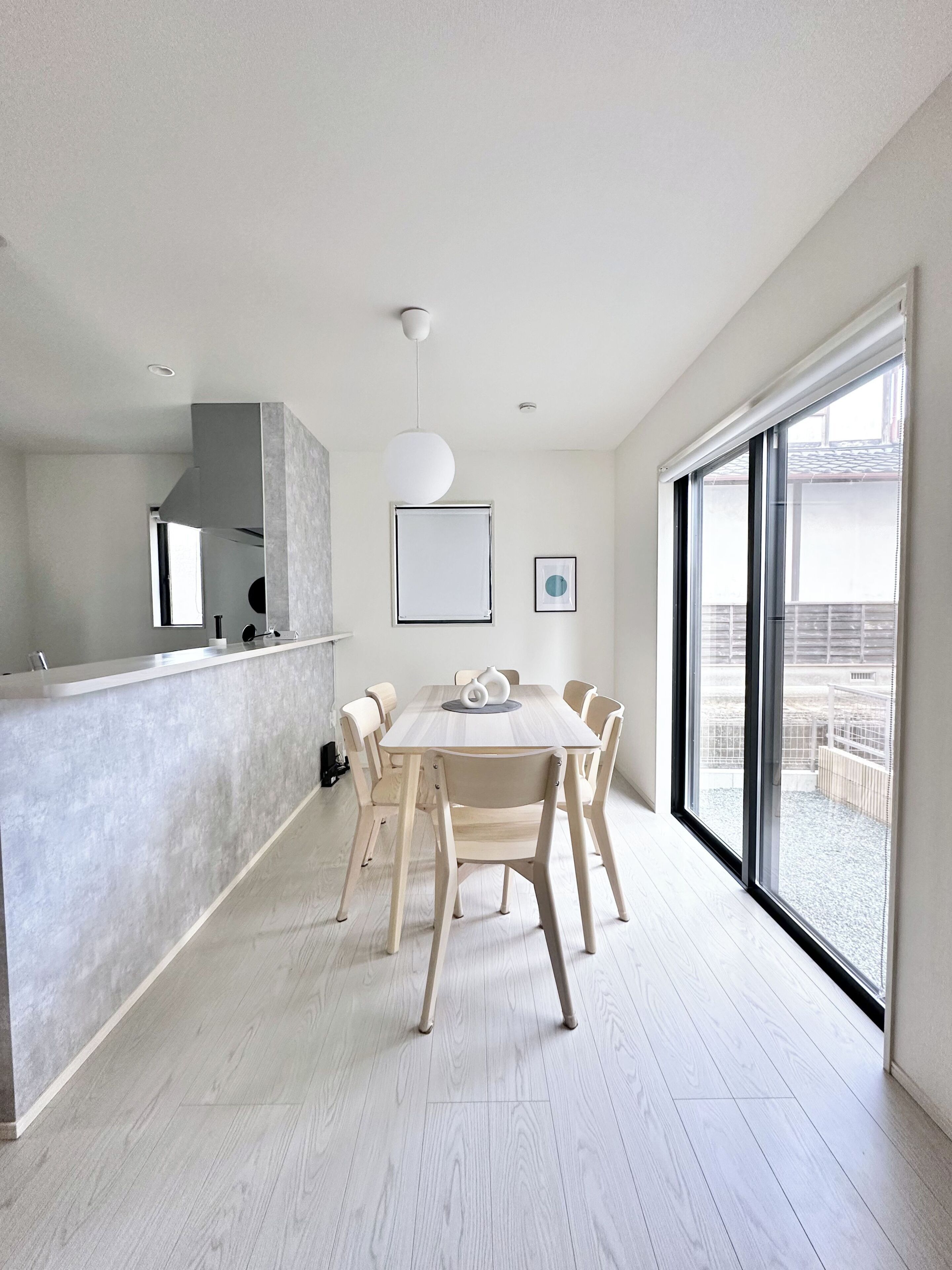 A modern kitchen with a central island, a dining area with a round table and chairs, and a large sliding glass door to the outside.