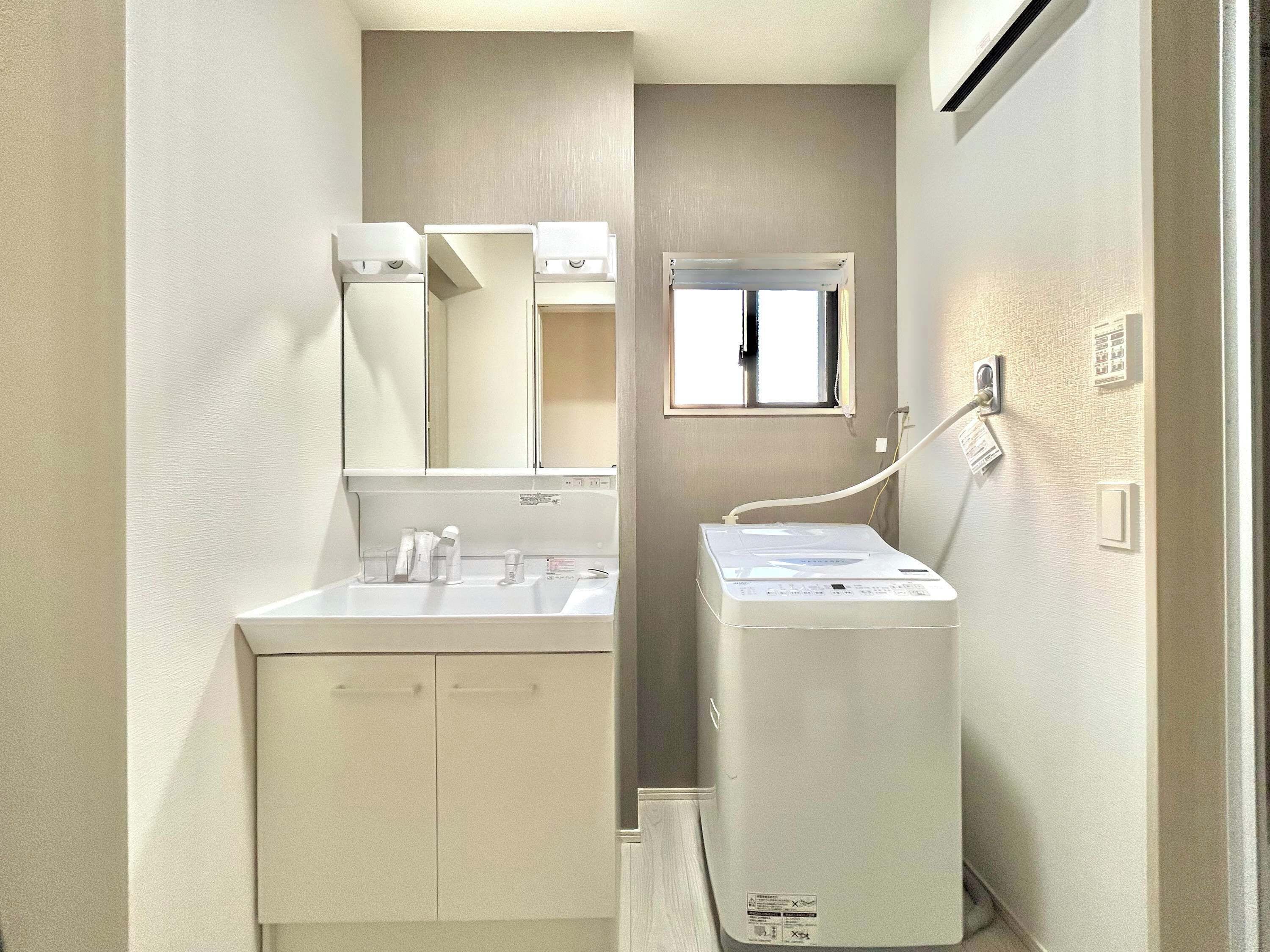 Un baño pequeño con lavamanos, espejo y lavadora y secadora compactas.
