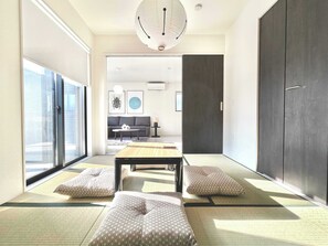 A modern living room with tatami mats, a low table, and cushions. - JP Ozu Units By Restavio (Ozu)