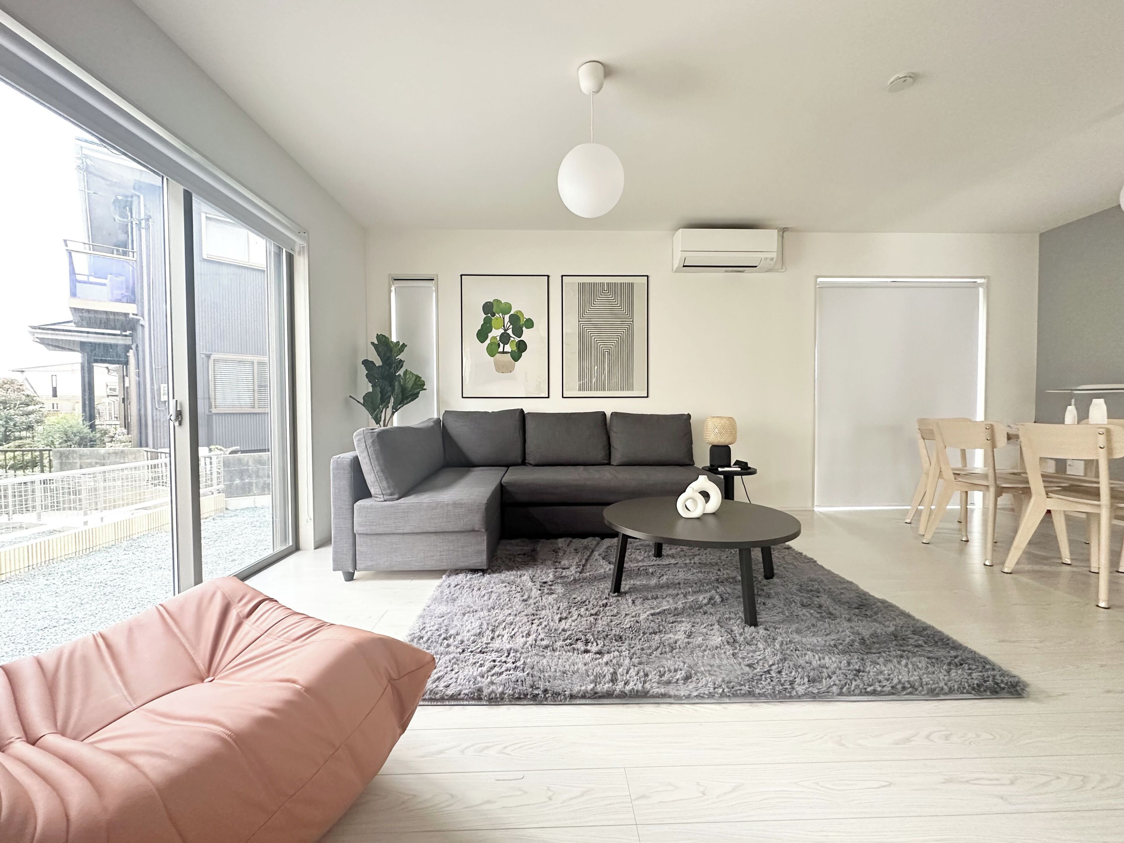 A modern living room with a sectional sofa, a round coffee table, and a dining area with wooden chairs.