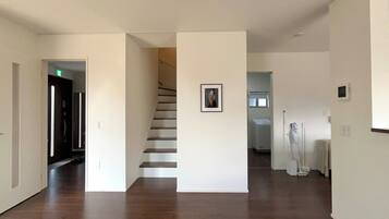 A spacious hallway with a wooden floor, a staircase, and a framed picture on the wall.