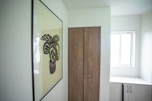 Habitació amb un armari de fusta, una finestra i una obra d'art emmarcada a la paret.