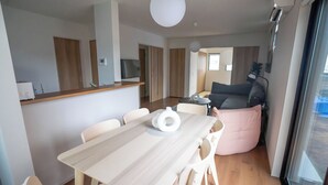 Moderni keittiö, jossa on ruokailutila, sohva ja suuri ikkuna.