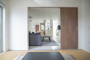 A modern hotel room with a bed, a desk, and a view into the dining area. - Otsu Hachibuko Homes By Restavio (Ozu)