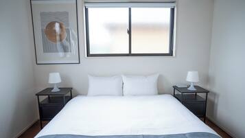 Een hotelkamer met een bed, twee nachtkastjes, een raam en een wandairconditioner.