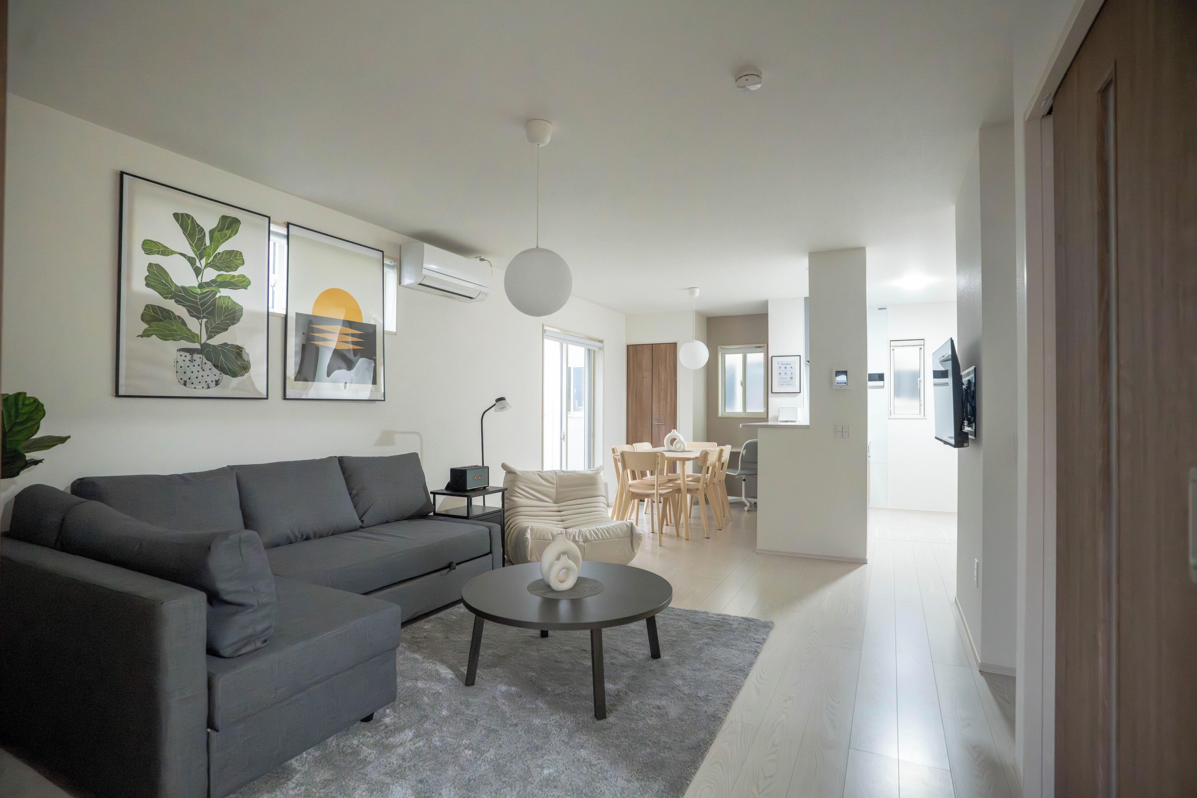 Un salon moderne avec un canapé gris, une table basse et des œuvres d’art accrochées au mur.