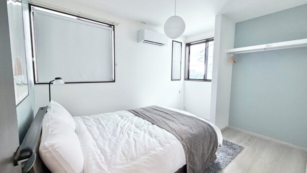 Ein modernes Schlafzimmer mit Bett, Nachttisch, Lampe und einem Fenster mit Jalousien.