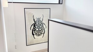 Eine Treppe mit einem gerahmten Kunstwerk von einem Käfer, einer weißen Wand und einem Lichtschalter.