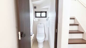 Un pasillo estrecho que conduce a un baño con inodoro, lavabo y ventana.