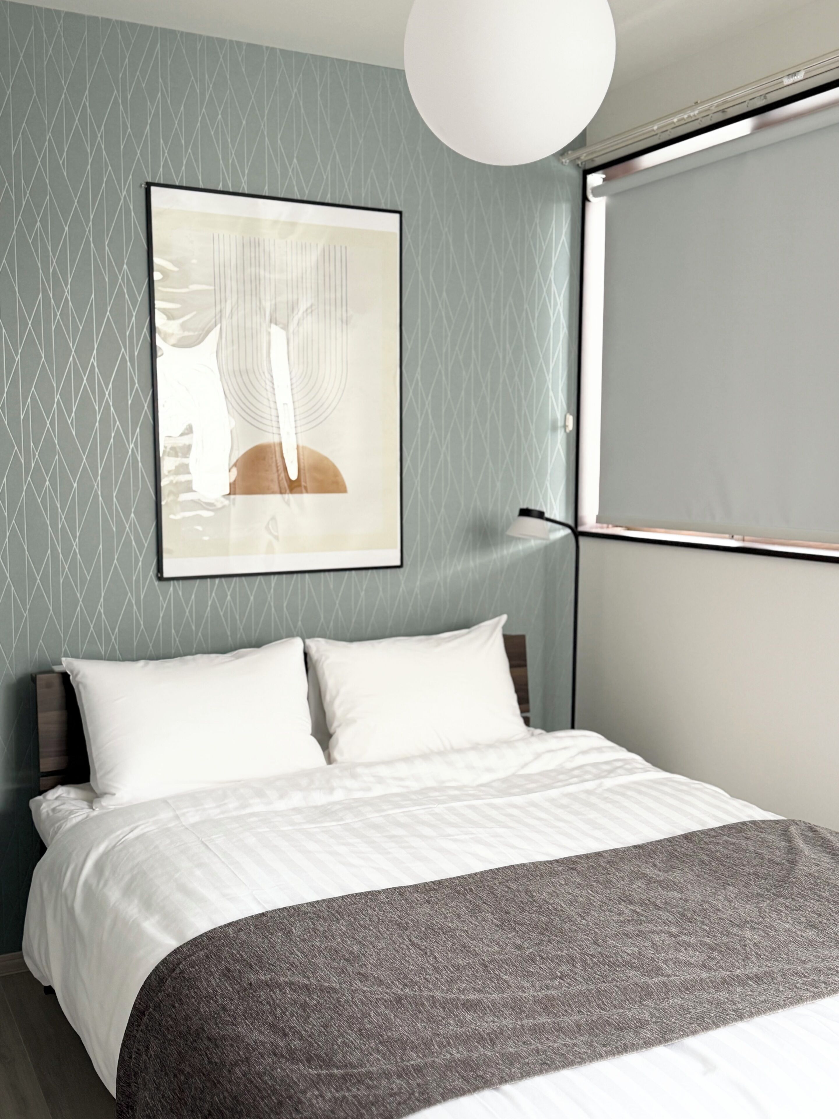 Un dormitorio moderno con cama, una obra de arte colgada en la pared y ventana con persianas.