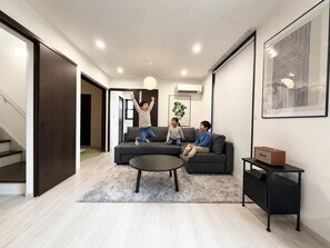 Una sala moderna con un sofá, una mesa de centro y una mesita auxiliar con un radio.