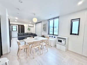 A modern living space with a dining area, sofa, and kitchen. - Modern Japanese House Near Ozu Station By Restavio (Ozu)