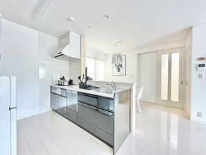A modern kitchen with a central island, stainless steel appliances, and a large window providing natural light. - Modern Property 15 Mins To Kumamoto Airport By Restavio (Ozu)
