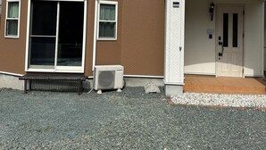 A two-story building with a brown and white exterior, a front door, and a bench outside. - Modern Property 15 Mins To Kumamoto Airport By Restavio (Ozu)