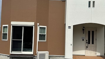 A two-story building with a brown and white exterior, a front door, and a bench outside.