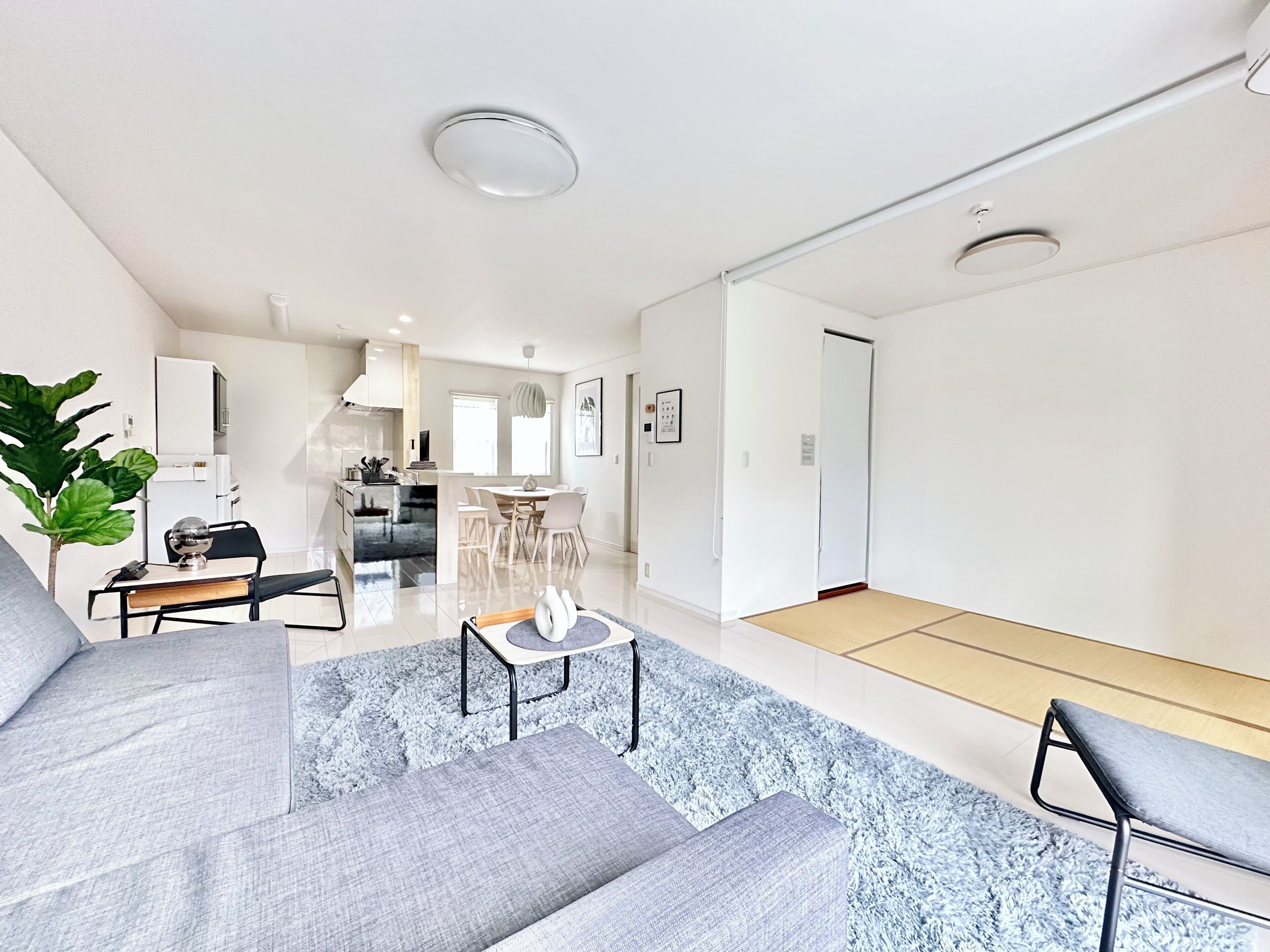 A modern living room with a sofa, a coffee table, and a dining area with chairs.