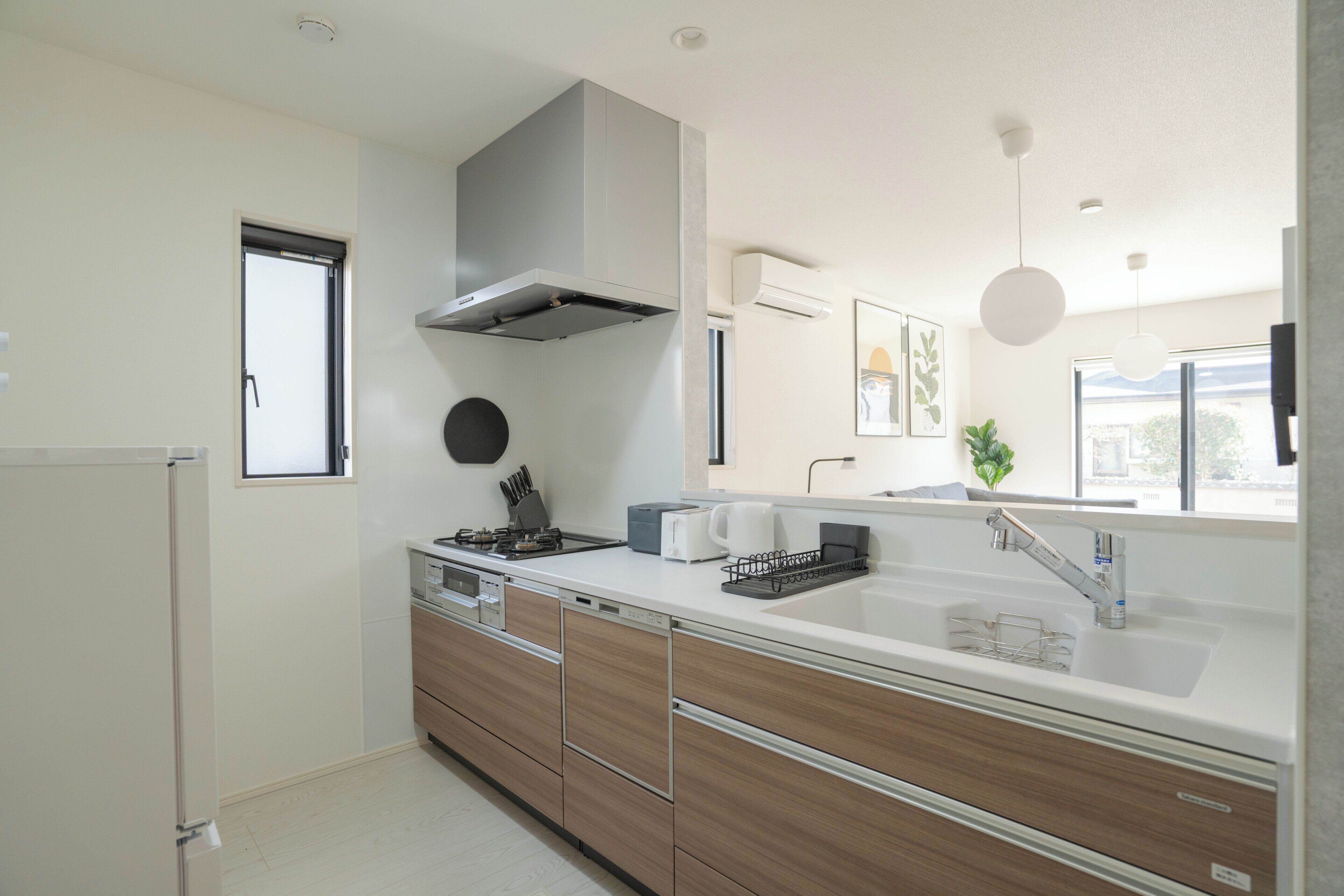 Une cuisine moderne dotée d’une cuisinière intégrée, d’une grande fenêtre et d’un évier avec un robinet contemporain.
