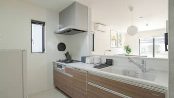 Une cuisine moderne dotée d’une cuisinière intégrée, d’une grande fenêtre et d’un évier avec un robinet contemporain.