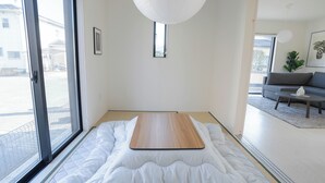 A minimalist bedroom with a bed, a wooden platform, and a view of the outside. - JP Sugimizu Units By Restavio (Ozu)