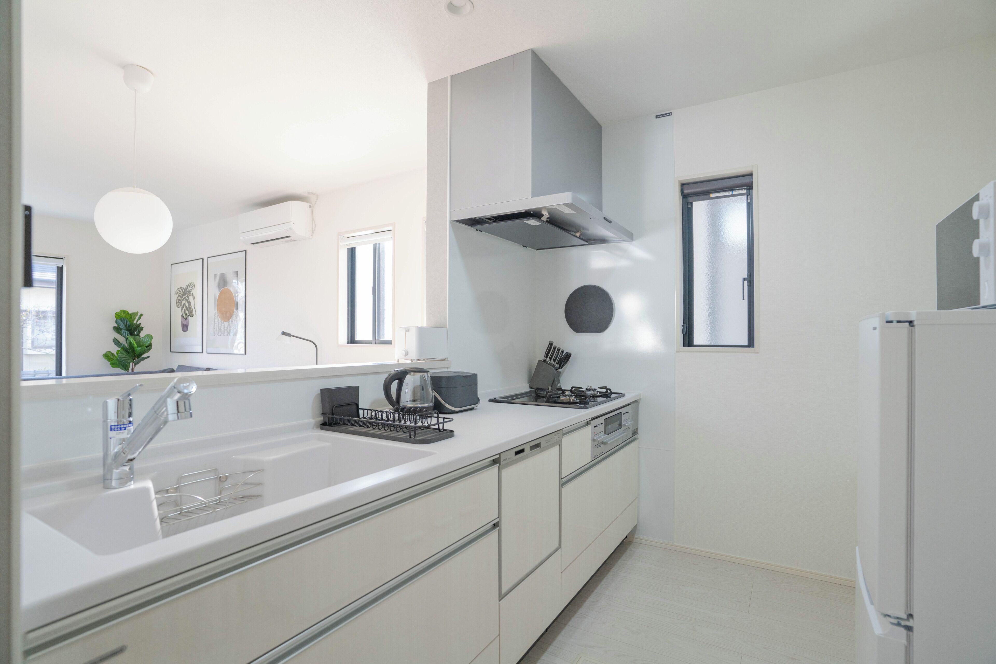 Una cocina moderna con encimera blanca, electrodomésticos de acero inoxidable y horno empotrado.