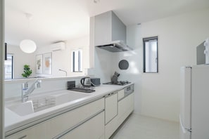A modern kitchen with a white countertop, stainless steel appliances, and a built-in oven. - JP Sugimizu Units By Restavio (Ozu)
