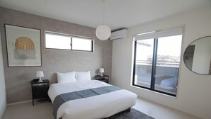 A modern bedroom with a large bed, two bedside tables, a floor lamp, a ceiling fan, a large window, and a wall-mounted mirror. - JP Sugimizu Units By Restavio (Ozu)