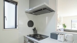 A compact kitchenette with a gas stove, a toaster, and a coffee maker. - JP Sugimizu Units By Restavio (Ozu)
