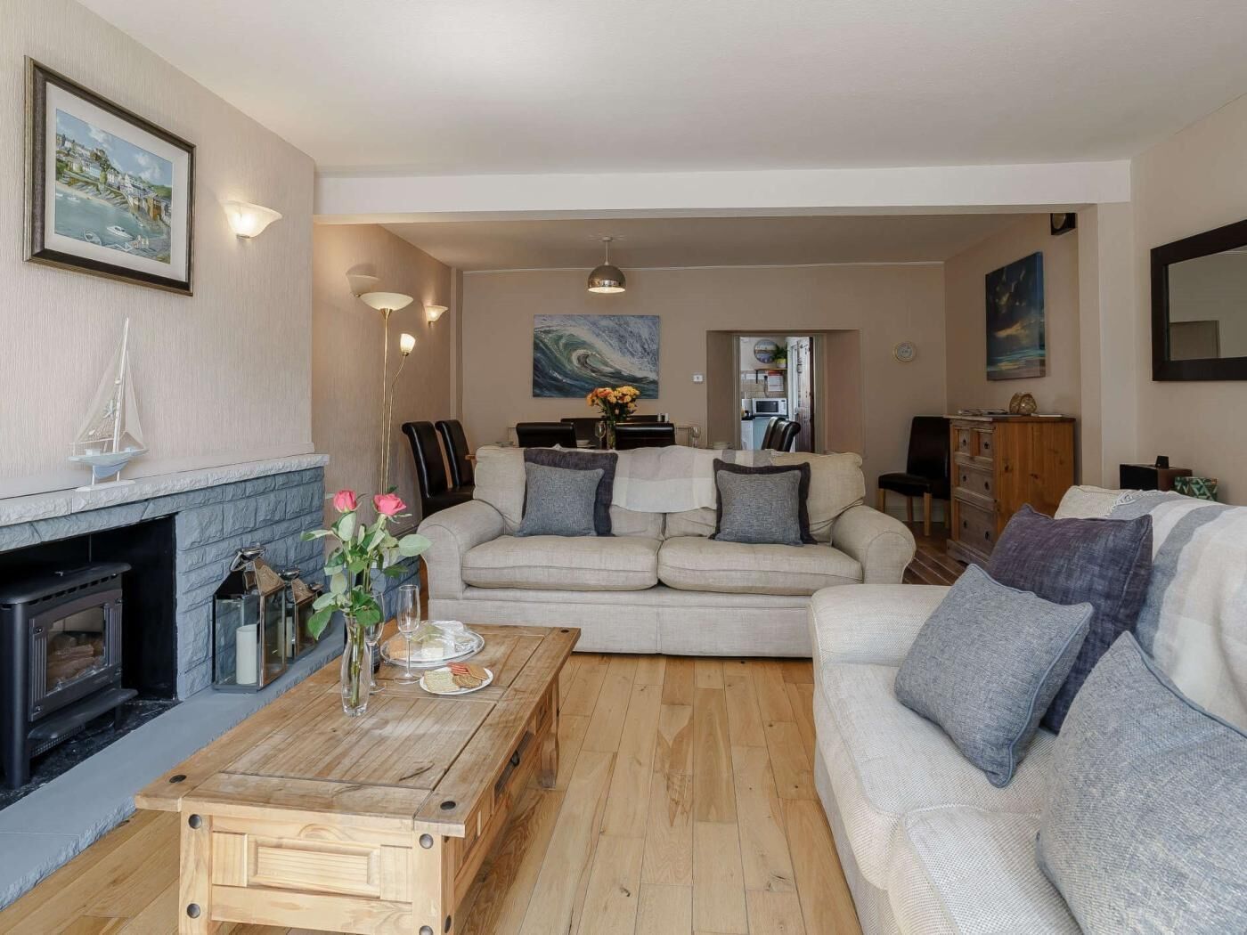 A living room with a fireplace, a sofa set, a wooden coffee table, and a painting on the wall.