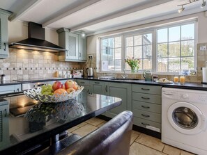 A kitchen with a central island, a washing machine, and a window with a view. - 4 Bed in New Quay (oc-78589) (New Quay)