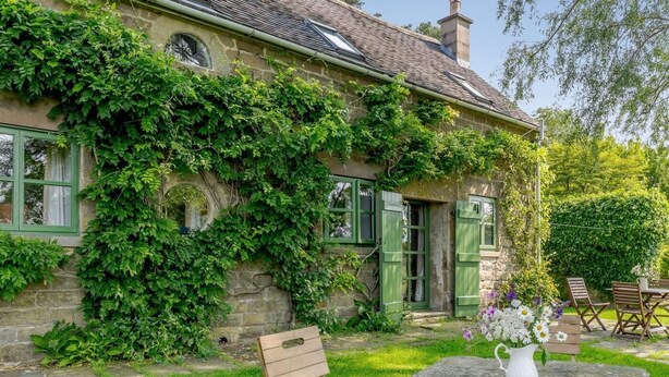 A stone house with green shutters, a garden with a stone table and chairs, and a white vase with flowers. - 3 Bed in Bakewell (oc-78618) (Gratton)