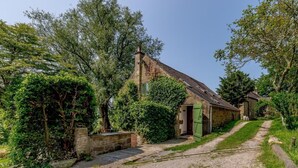 A rustic stone house with a gravel path leading to a green door, surrounded by lush greenery. - 3 Bed in Bakewell (oc-78618) (Gratton)