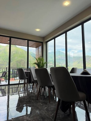 Una sala de conferencias con vistas a colinas verdes, ventanas amplias y sillas modernas.