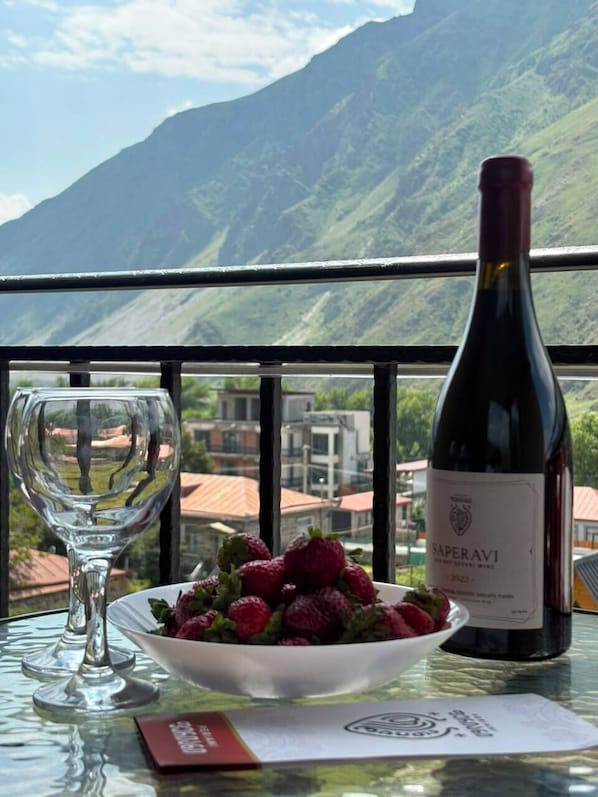 Una mesa con una botella de vino, una copa y un bol de fresas.