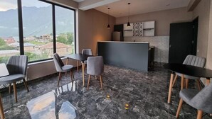Un interior moderno con comedor, cocina y ventanas grandes con vistas a un paisaje montañoso.