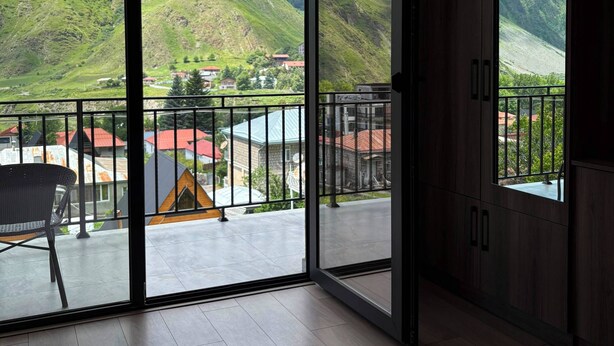 Una habitación con un gran ventanal corredero que da a un balcón con vistas a la montaña.