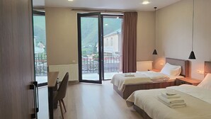 Habitación de hotel con dos camas, un escritorio y vistas al exterior.