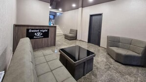Zona de recepción con un sofá, sillas, una mesa de centro y un cartel que dice 'Sweet night Reception'.